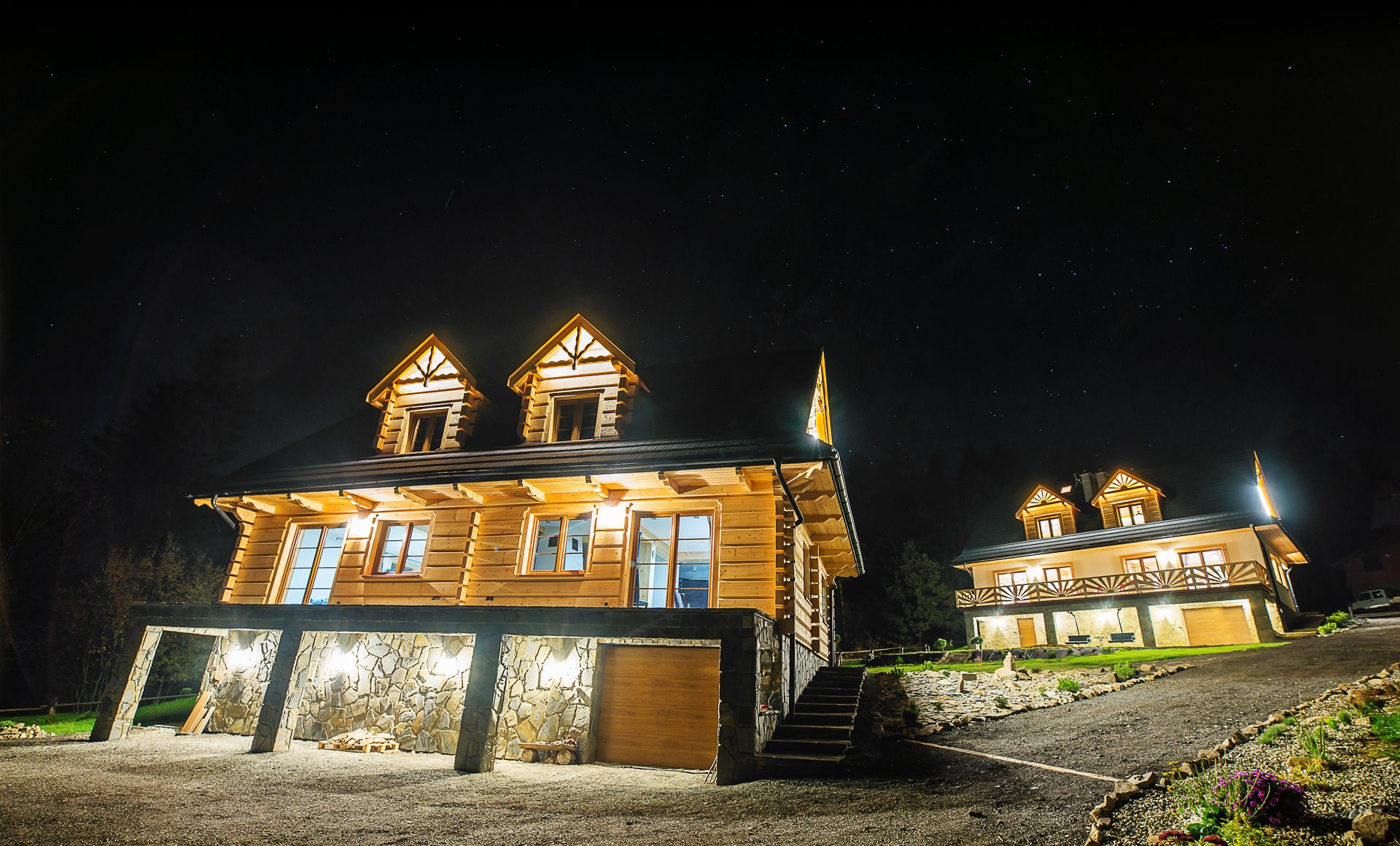 Oświetlone domki z bali na tle rozgwieżdżonego nieba