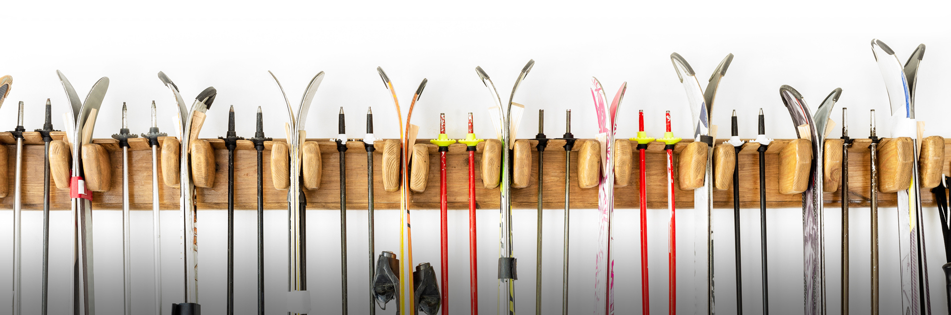 Narty i kijki narciarskie zawieszone na drewnianym uchwycie